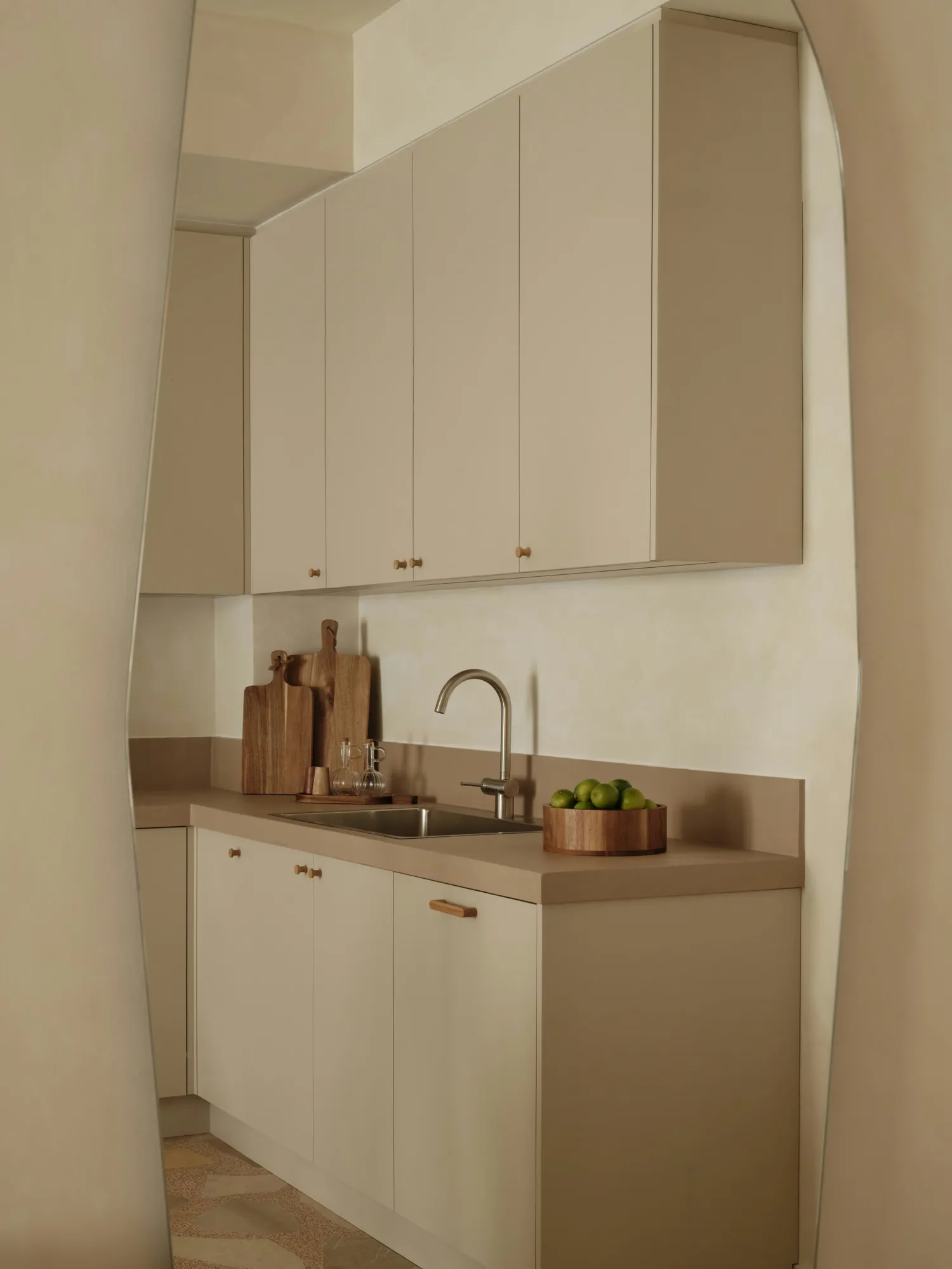 Detail of the kitchen sink, brass fittings and pale cabinetry