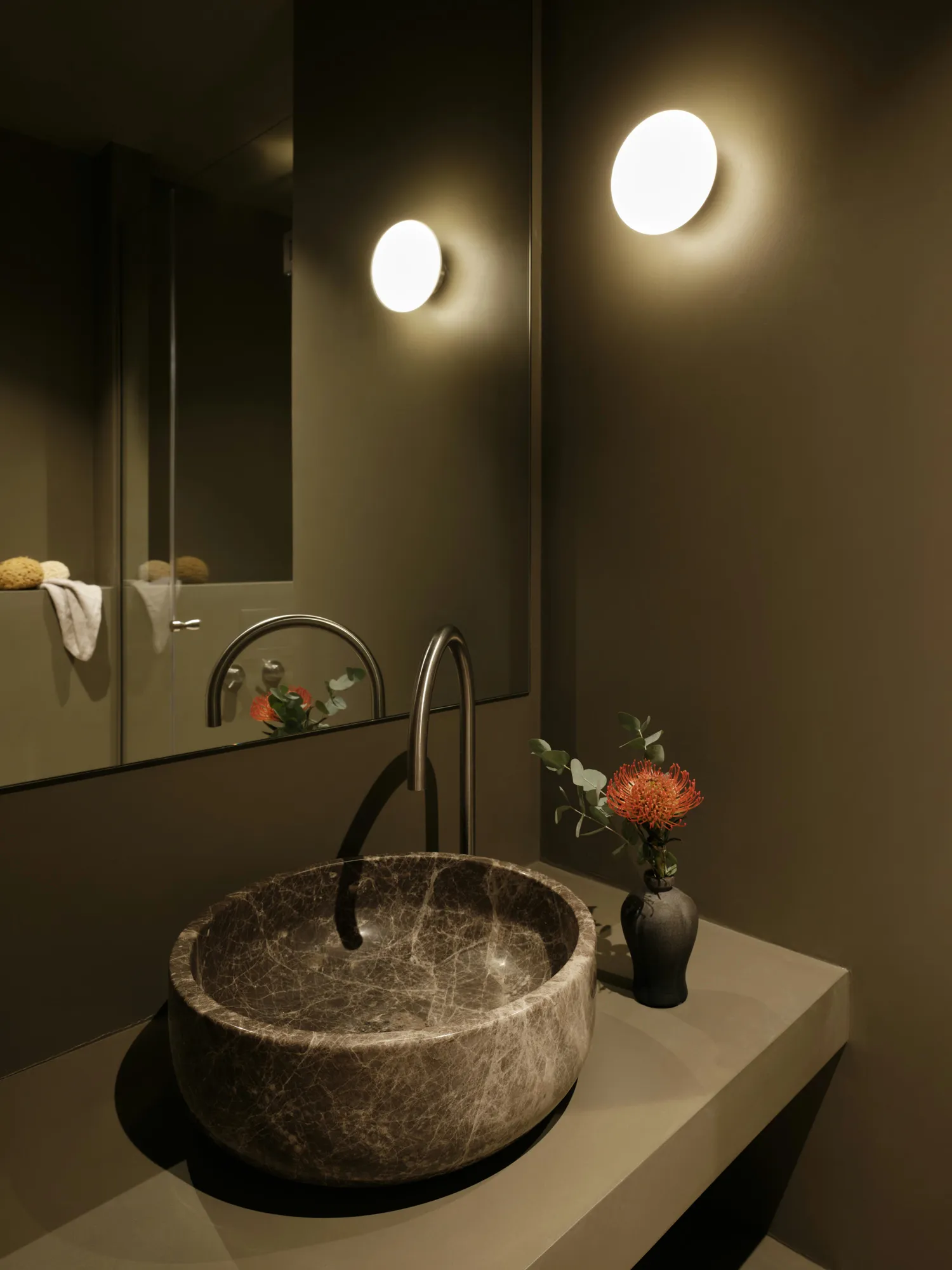 Bathroom vanity with dark walls and a stone basin