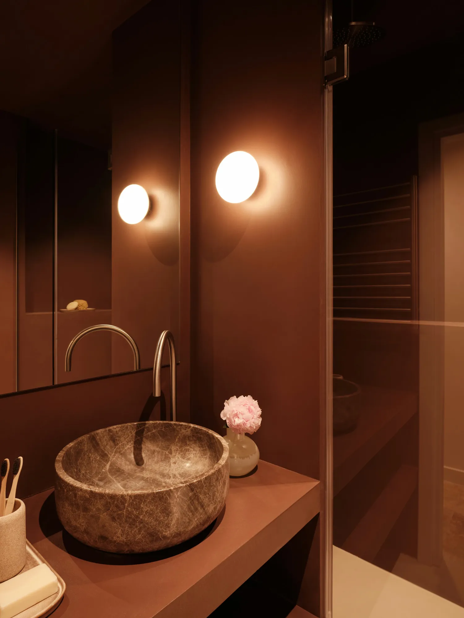 Terracotta-toned bathroom with illuminated mirrors