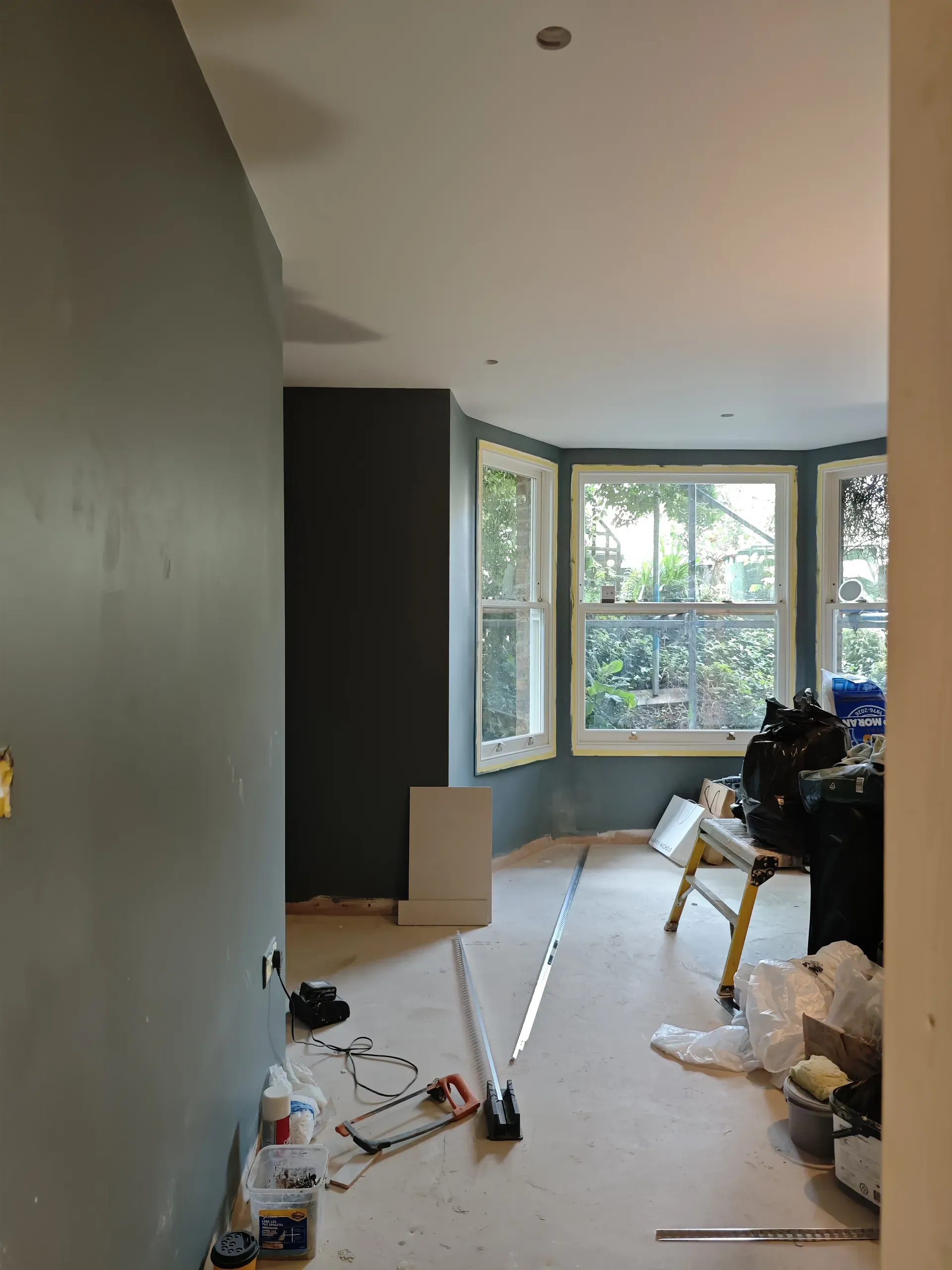 Bay-windowed room during painting and floor preparation