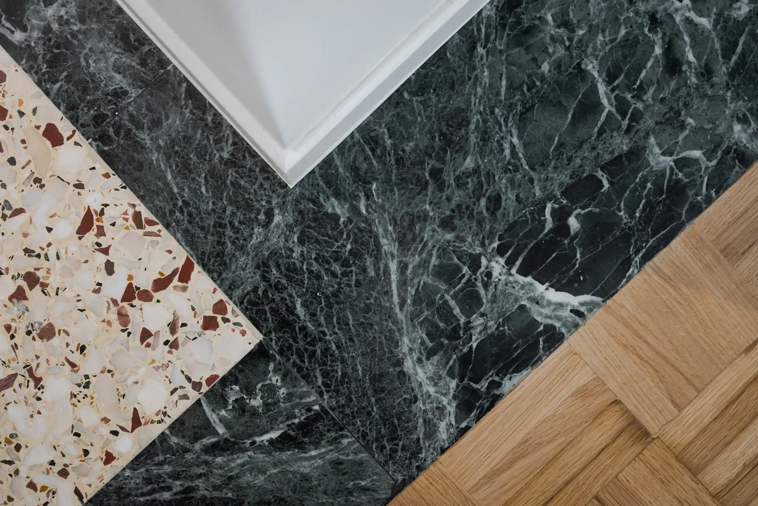 Junction of restored terrazzo, dark Tinos marble and oak parquet floors in an Athens apartment