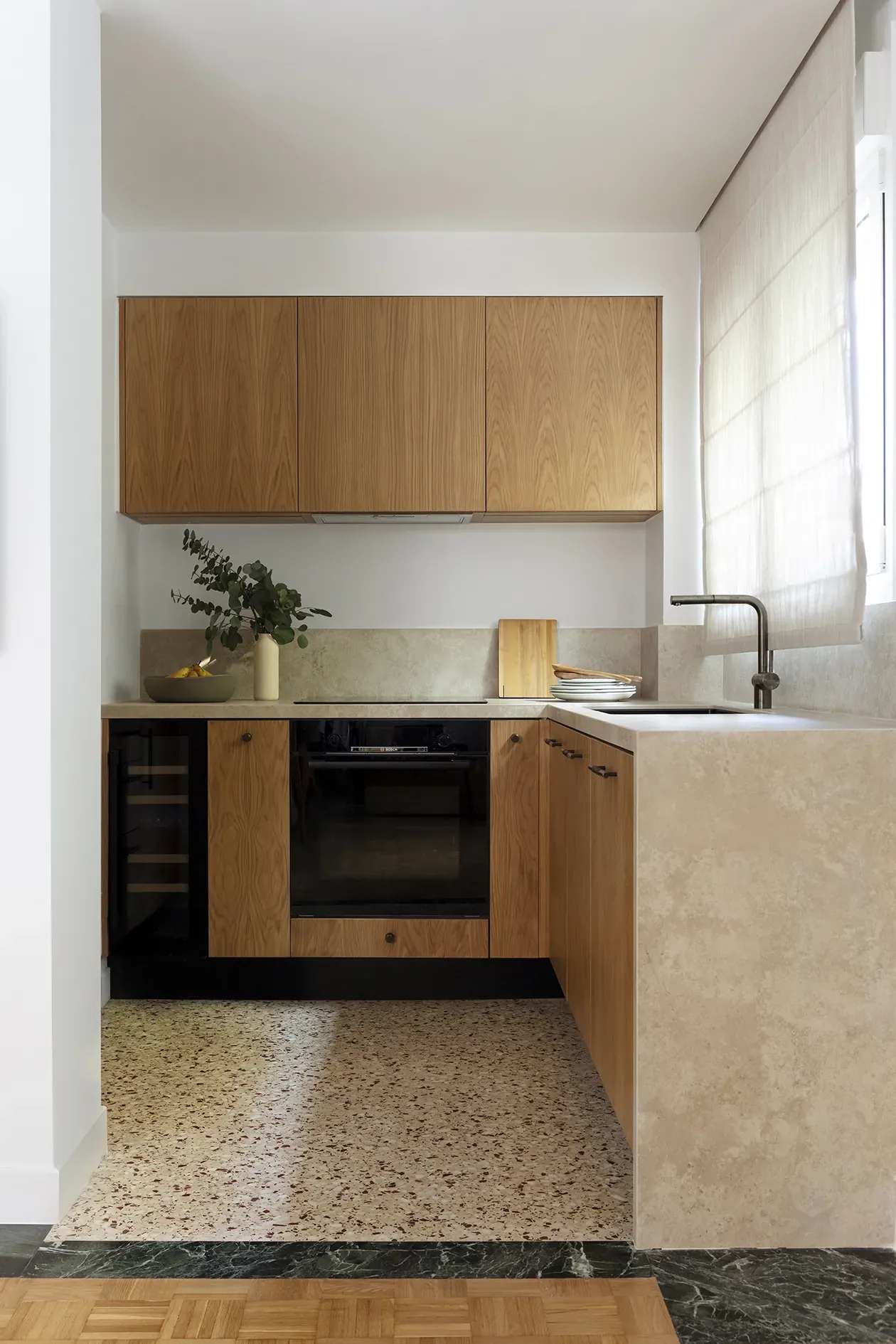 Compact kitchen with oak cabinetry, stone worktops and a restored terrazzo floor