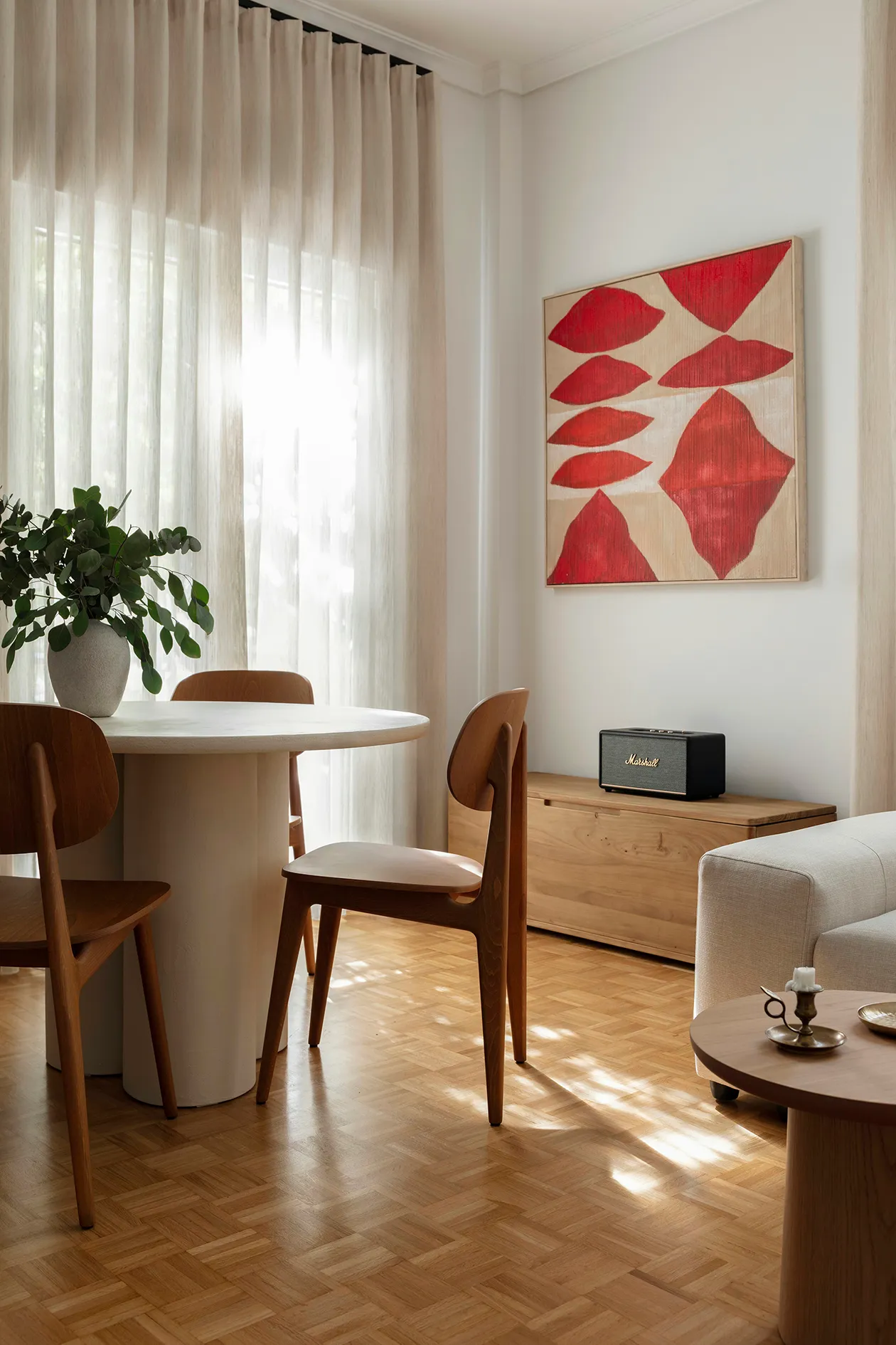 Round dining table and timber chairs beside the sunlit living area