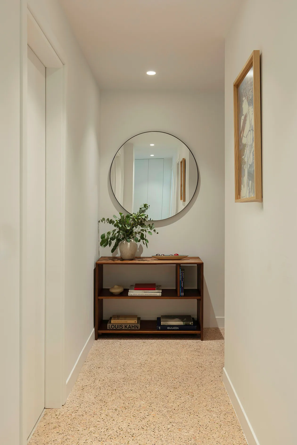 Entrance hall with restored terrazzo floor, timber console and round mirror