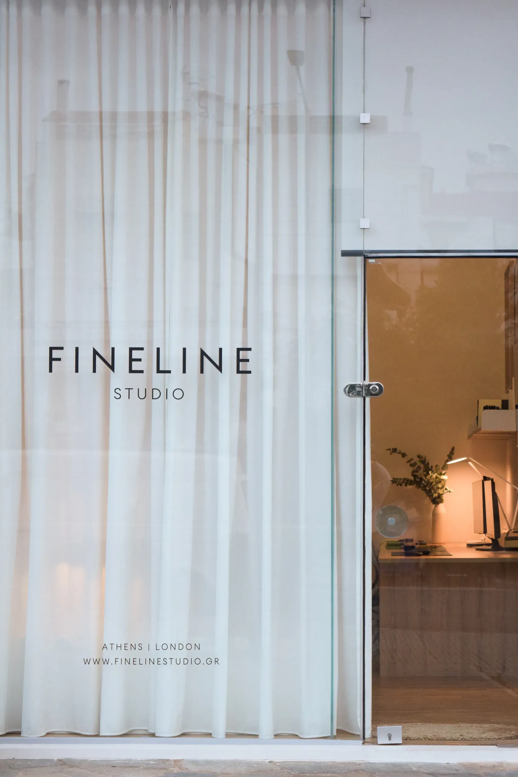 Fineline Studio's glazed shopfront with a sheer curtain and view into the office