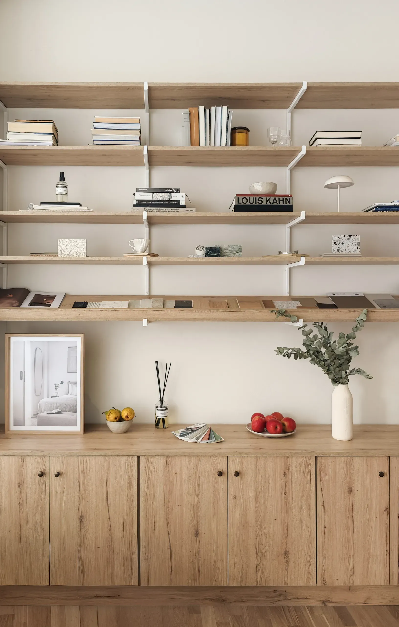 Full-height timber shelving displaying books, objects and material samples