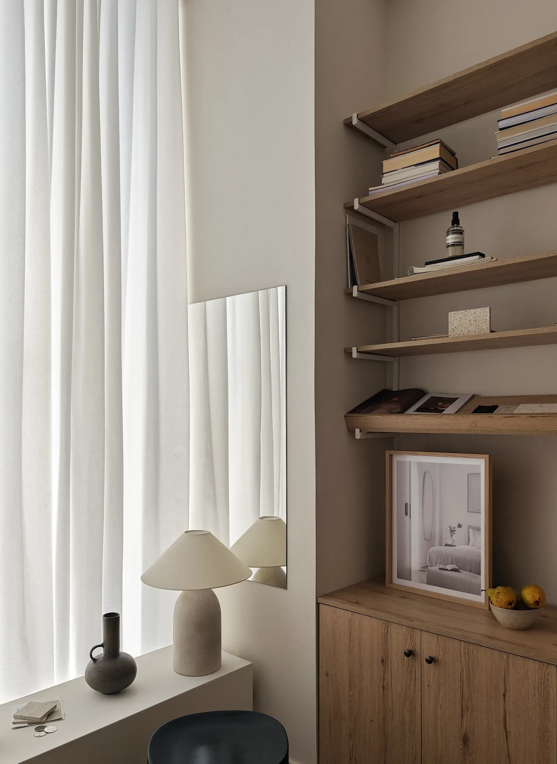 Mirror, table lamp and open timber shelving beside the studio curtain