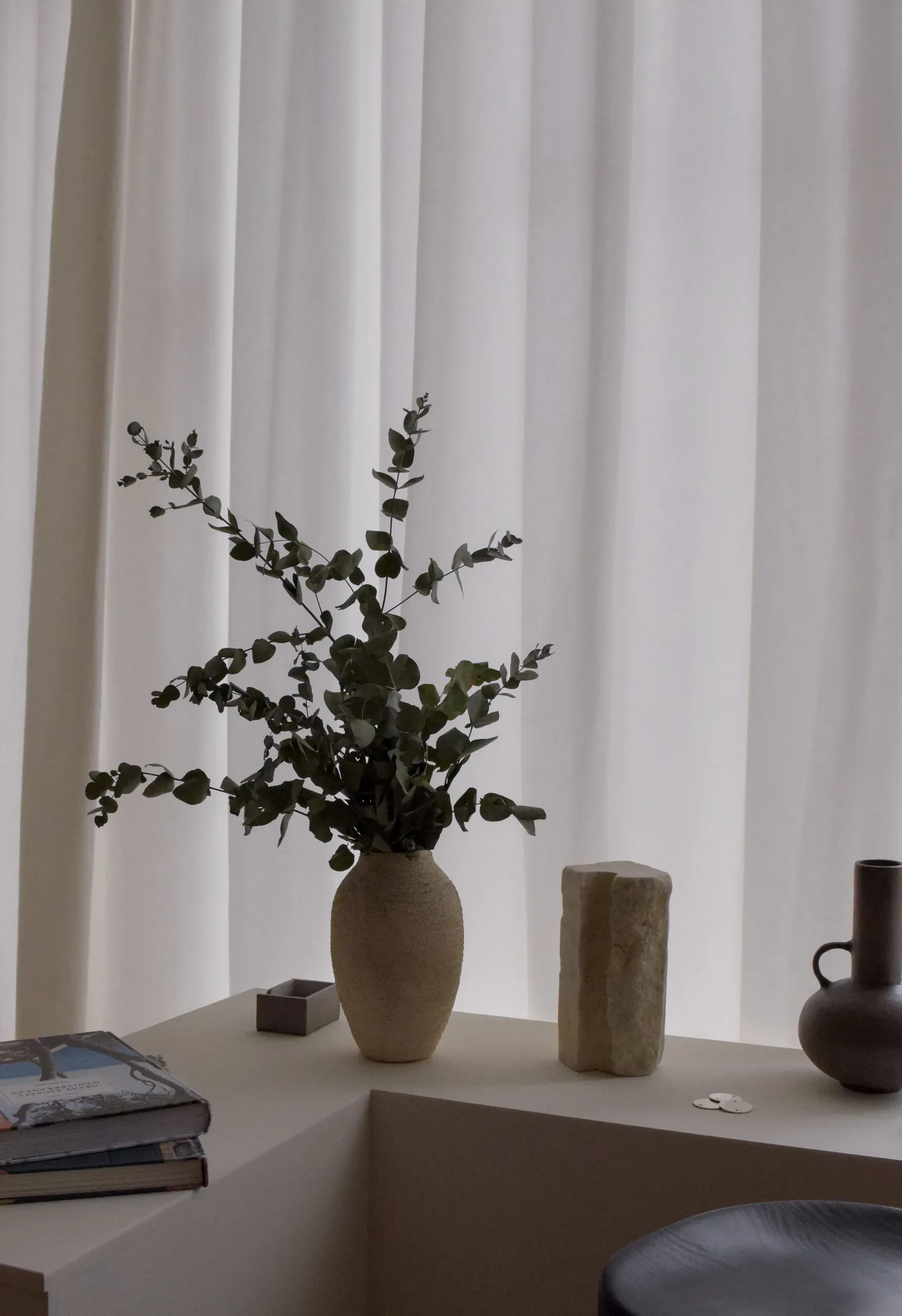 Vases and eucalyptus arranged in front of the softly lit curtain