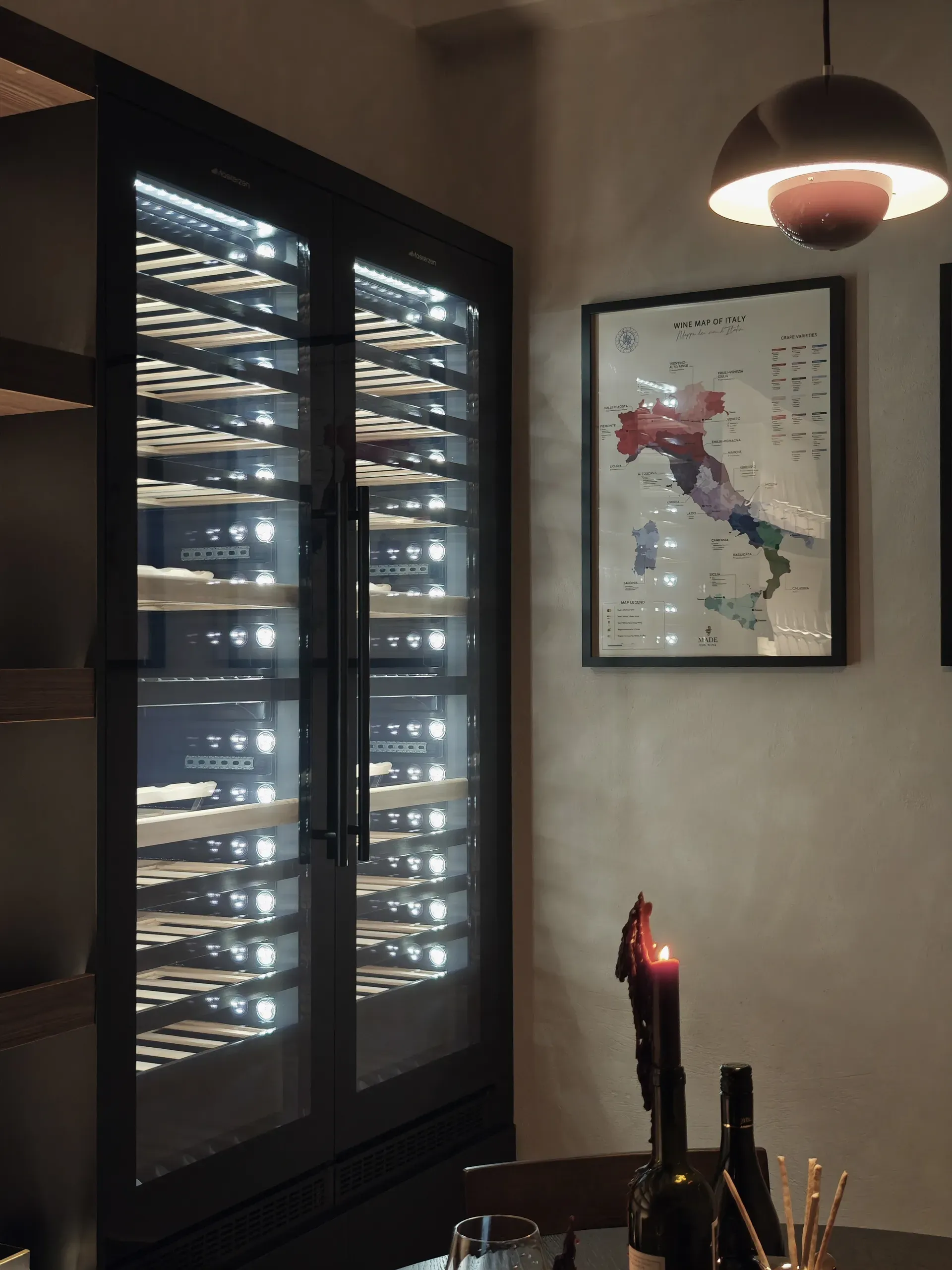 Illuminated wine refrigerators beside a framed map of Italian wine regions