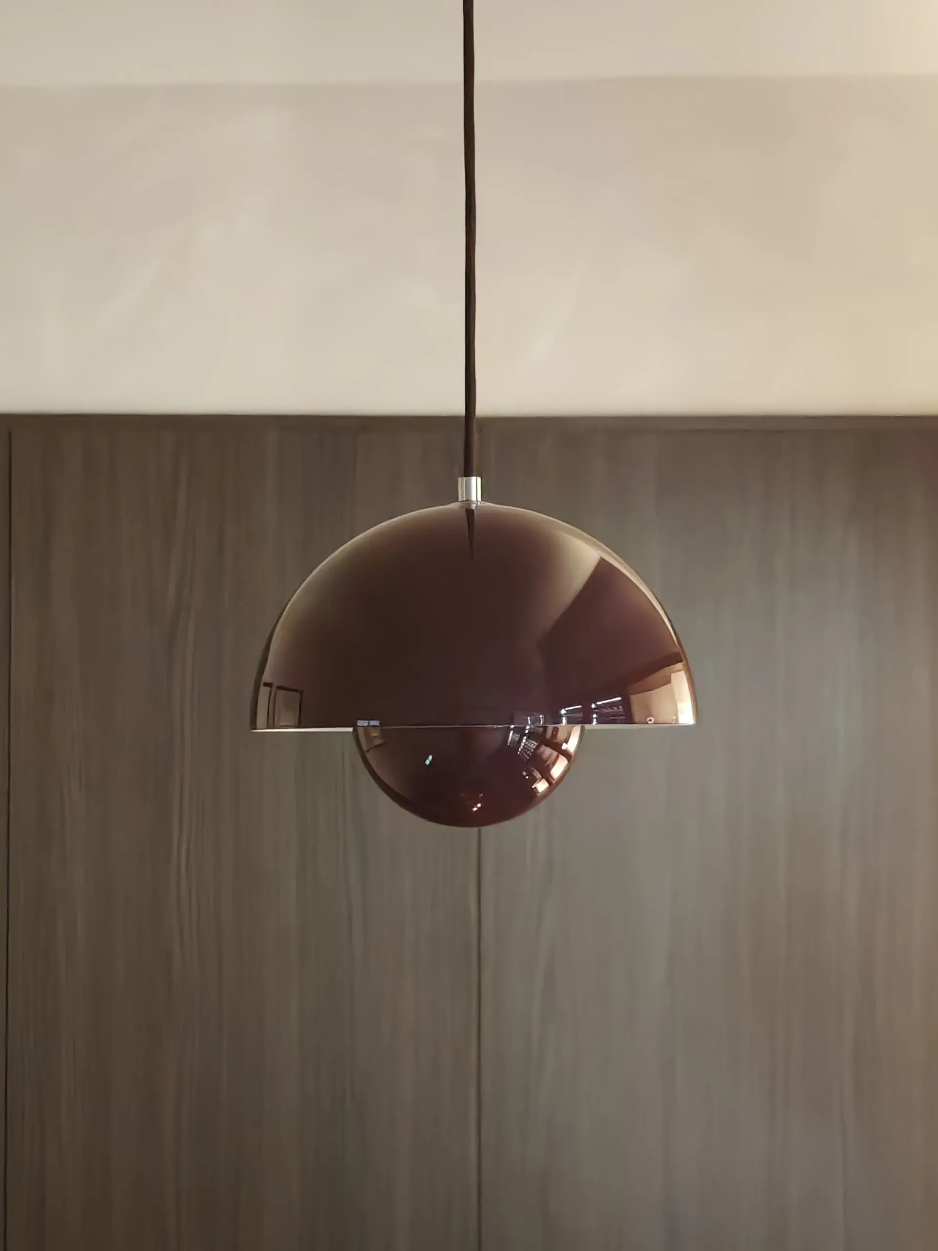 Sculptural burgundy pendant light against dark timber wall panelling