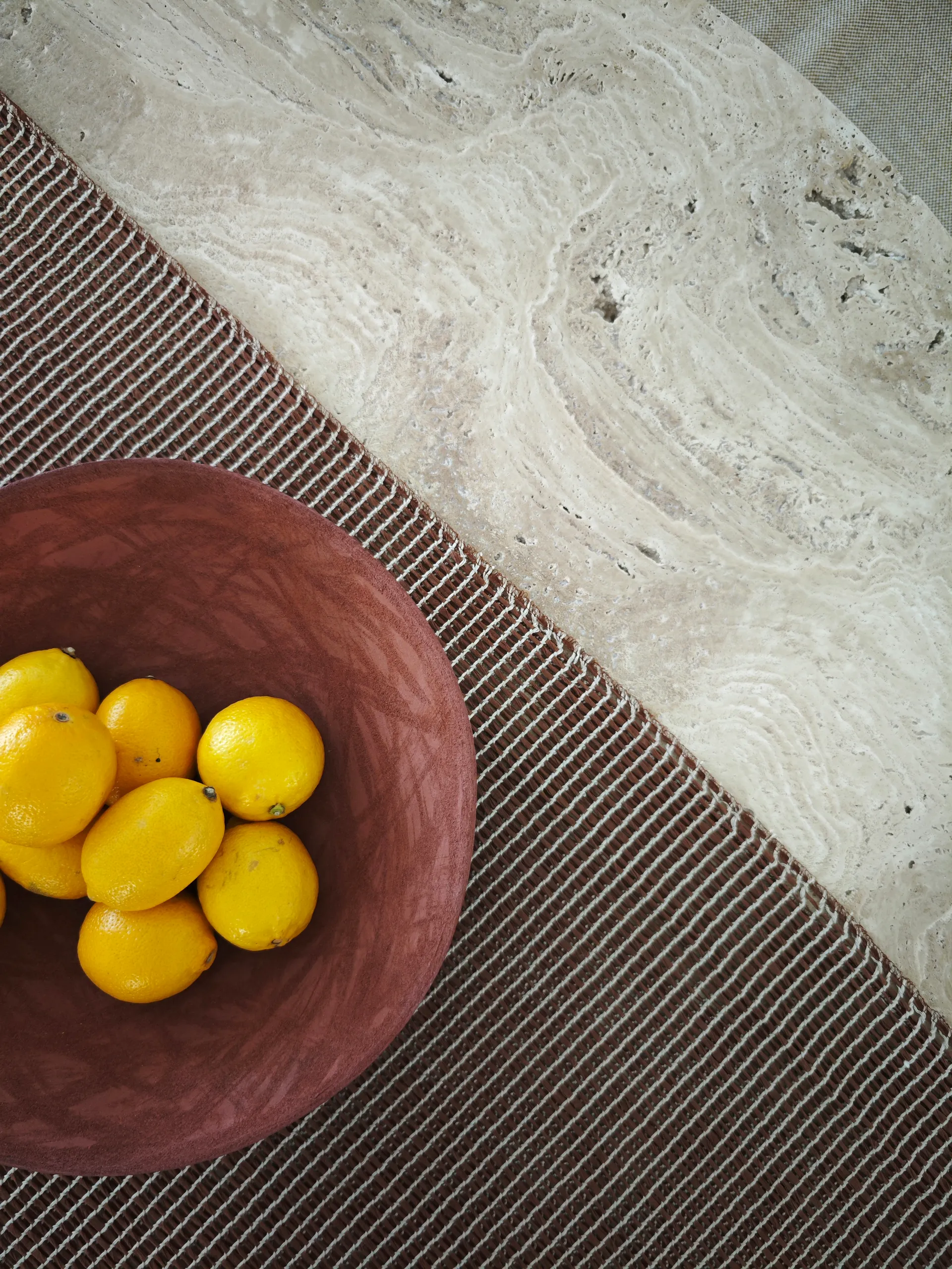 Detail of a circular travertine table with a bowl of lemons